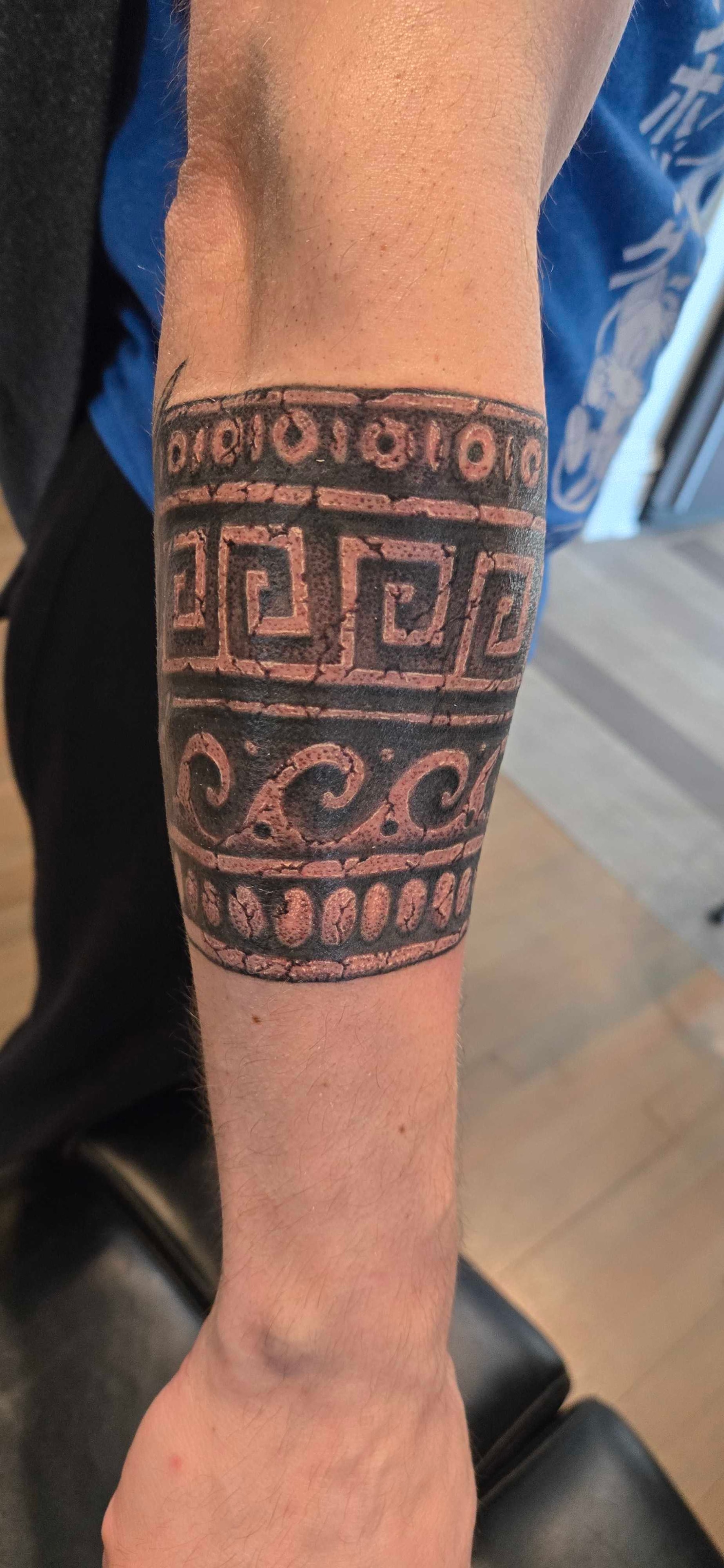 Blackwork armband tattoo with geometric and wave motifs