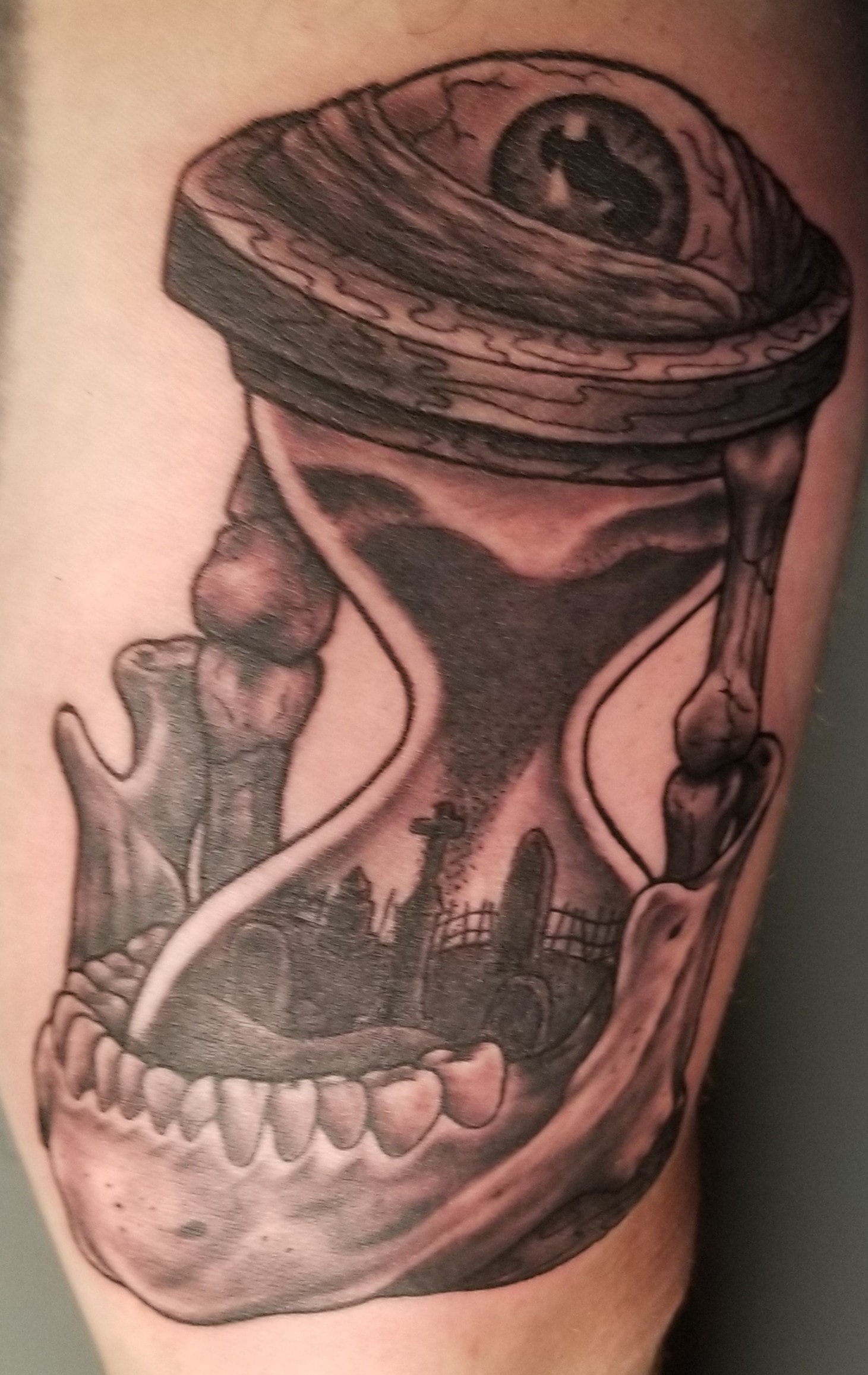 Black and gray custom tattoo of a skull wearing a hat with ornamental details
